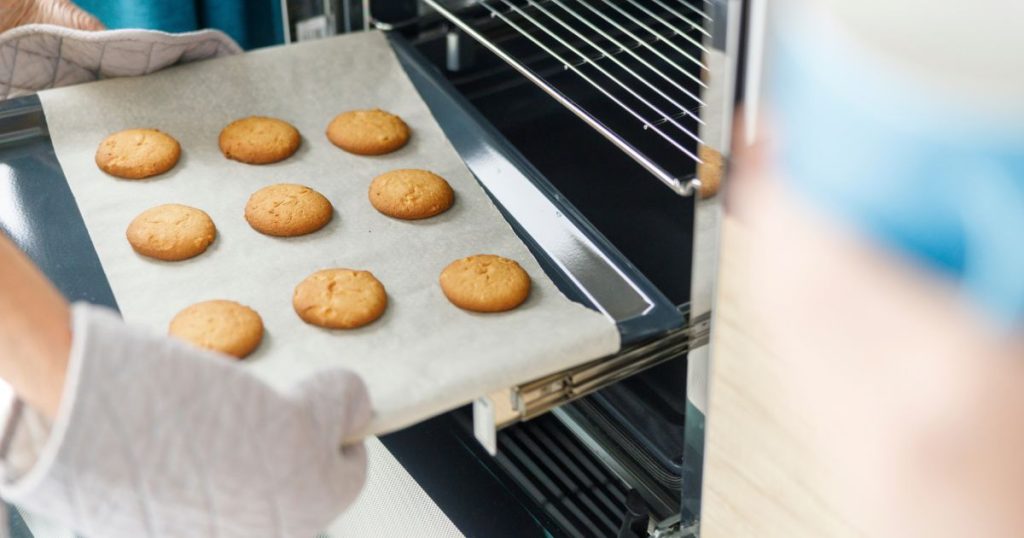 woman is taking baking tray with baking